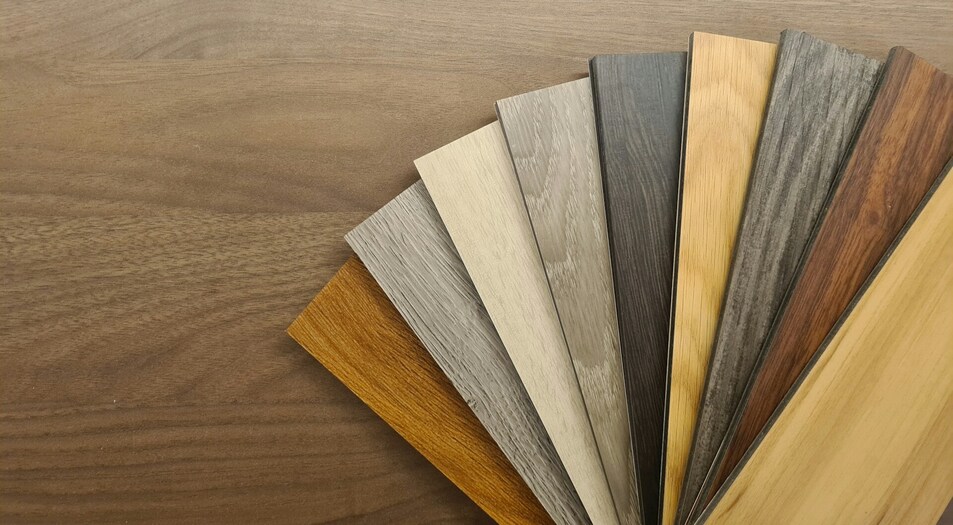 laminate floor planks next to engineered floor planks and solid hardwood planks laid out on a display floor