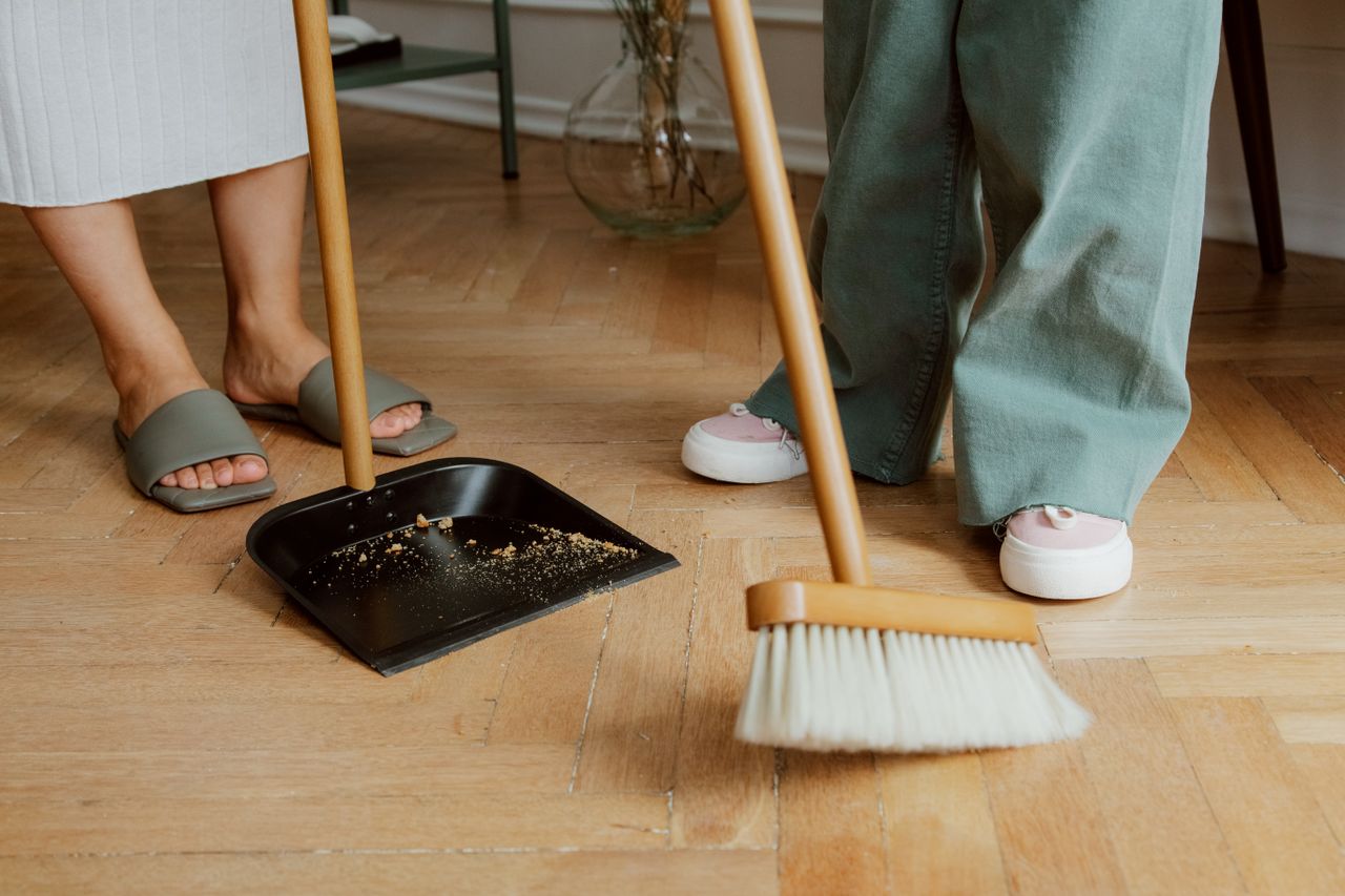 two people helping each other clean up a mess on their engineered hardwood floors